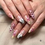 The nails feature a mix of solid white with dark red polka dots, beige and pink floral swirls, and a small 3D white bunny with black ears on one nail.