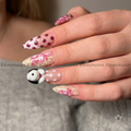 The nails feature a mix of solid white with dark red polka dots, beige and pink floral swirls, and a small 3D white bunny with black ears on one nail.